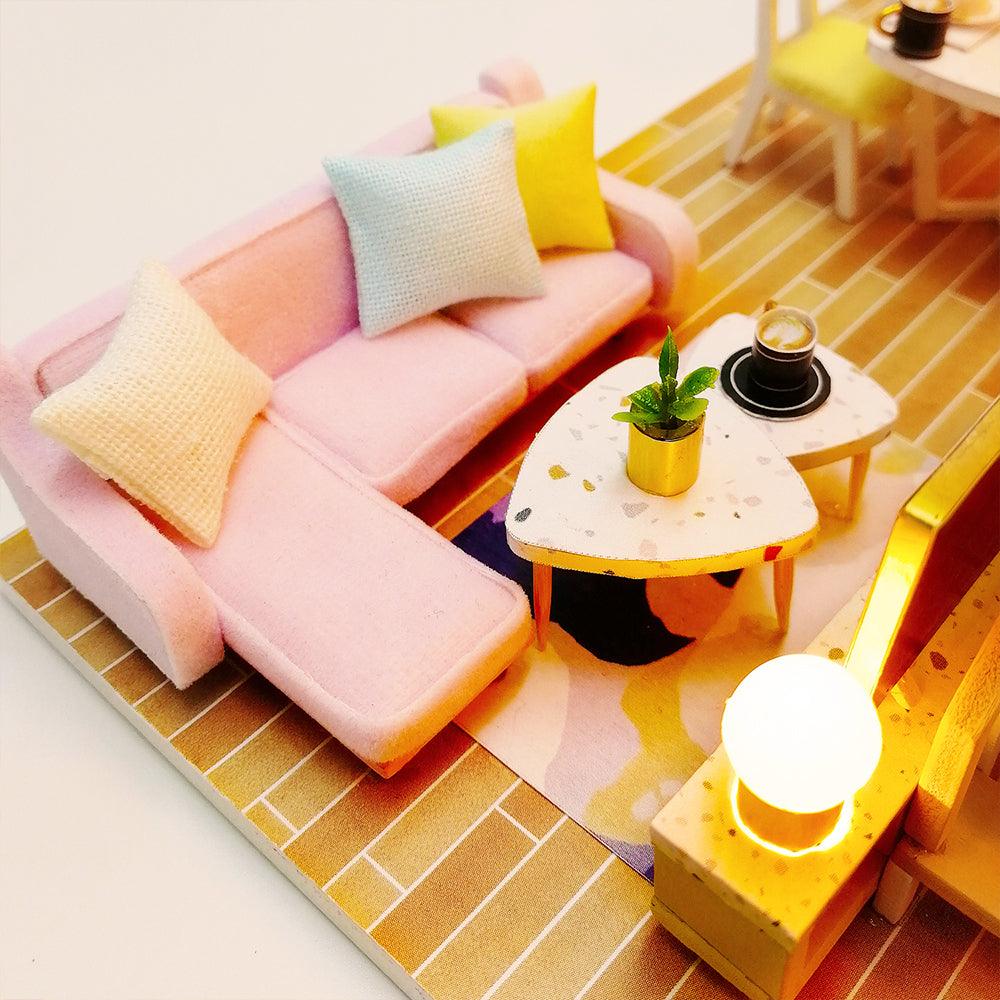 Miniature living room with a pastel sofa, coffee table and a glowing LED lamp, a cozy room box for shelf decor
