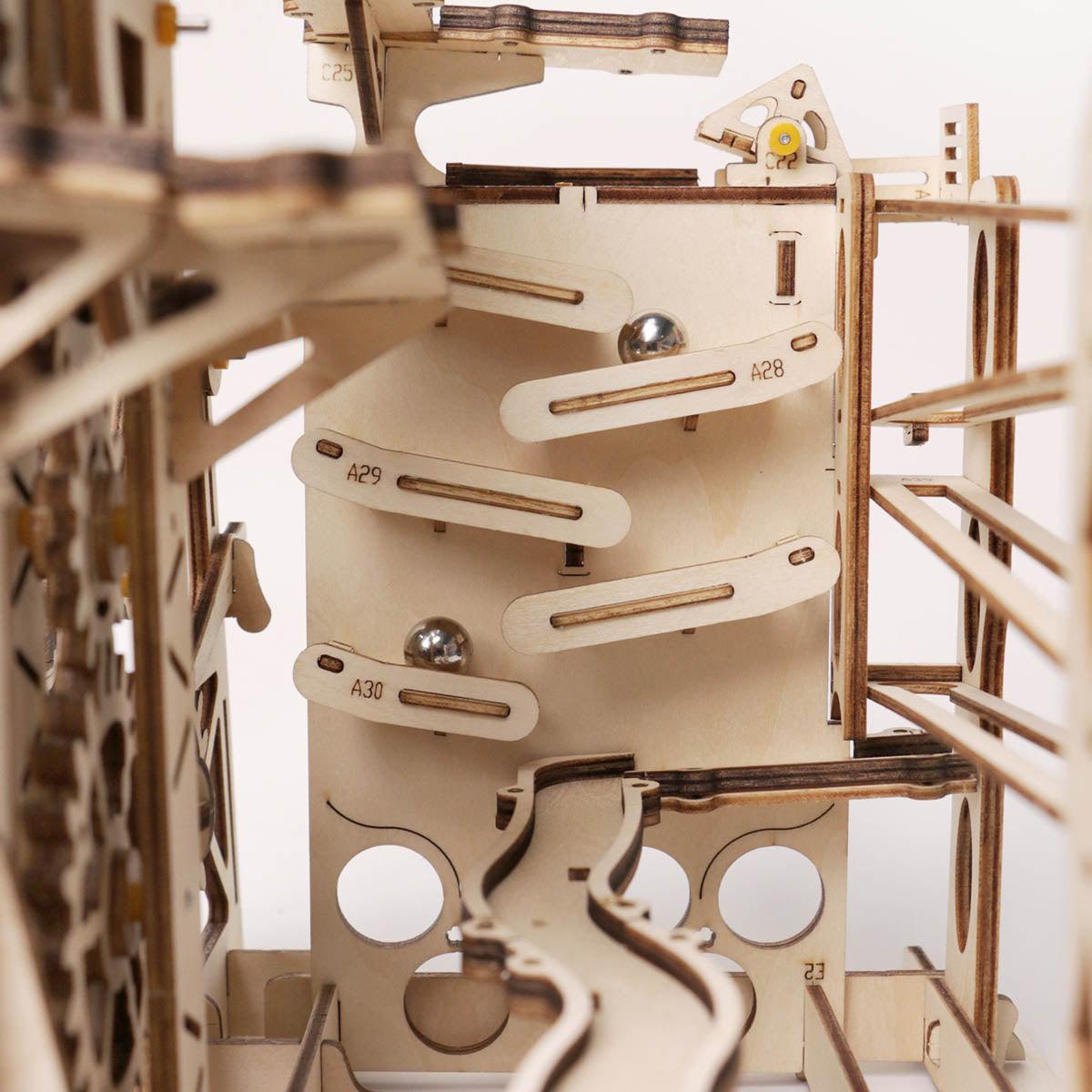 Close swingback rail system guiding marbles down winding wooden ramps, a working kinetic marble machine for STEM learners