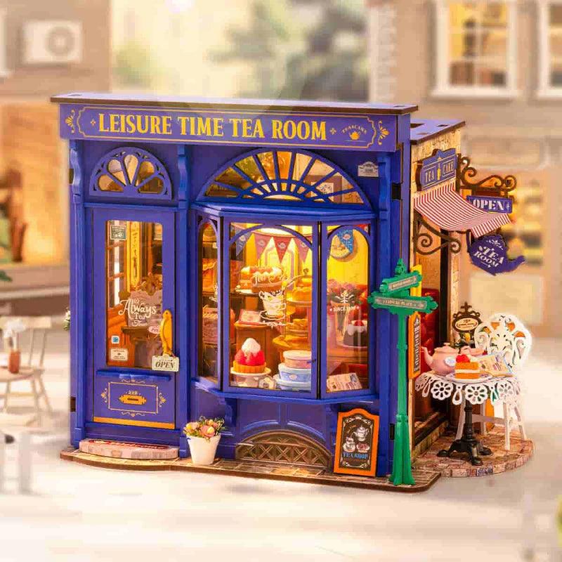 Miniature cafe kit with a warm lit window display of tiny cakes and treats, a handmade tea shop scene for hobbyists