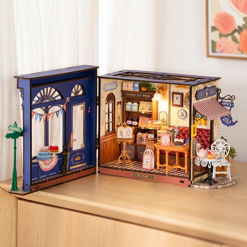 Miniature tea room box interior with stocked shelves and a wood counter, a furnished cafe dollhouse build for crafters
