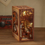 Assembled book nook shelf insert with warm lighting and a phonograph as a music-themed miniature room between books SZ003