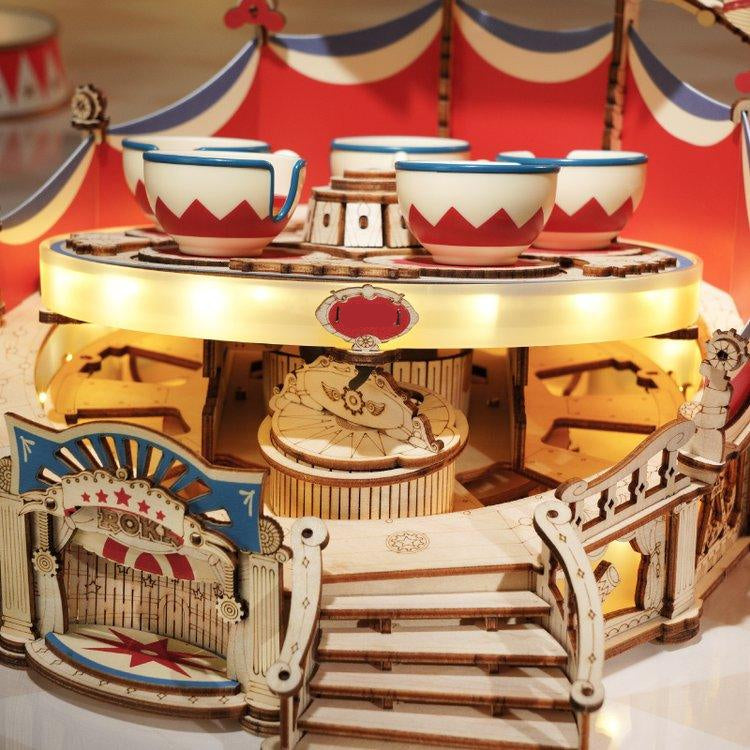 Five spinning teacups on a rotating chassis driven by a wind-up music box, a mechanical wooden puzzle for adults