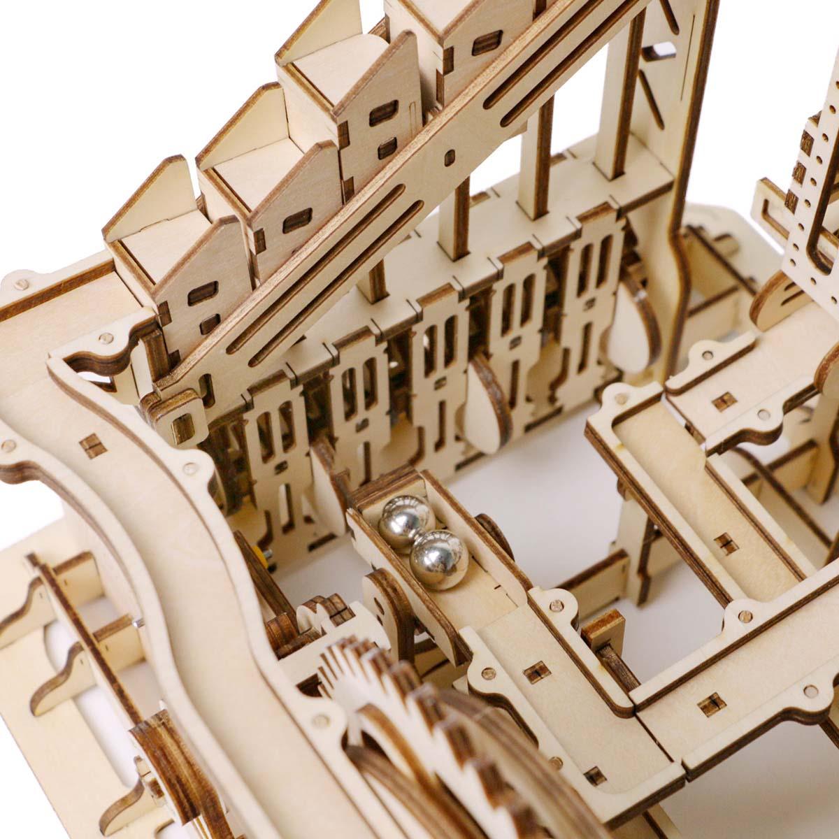 Detailed trapdoor track system and wooden gears steering marbles down surprise pathways, a kinetic STEM building toy