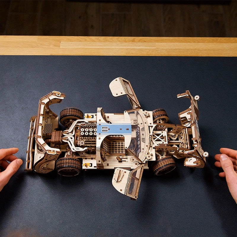 Wooden race car model with natural plywood grain and a smooth aerodynamic body, a 3D mechanical puzzle for adult hobbyists