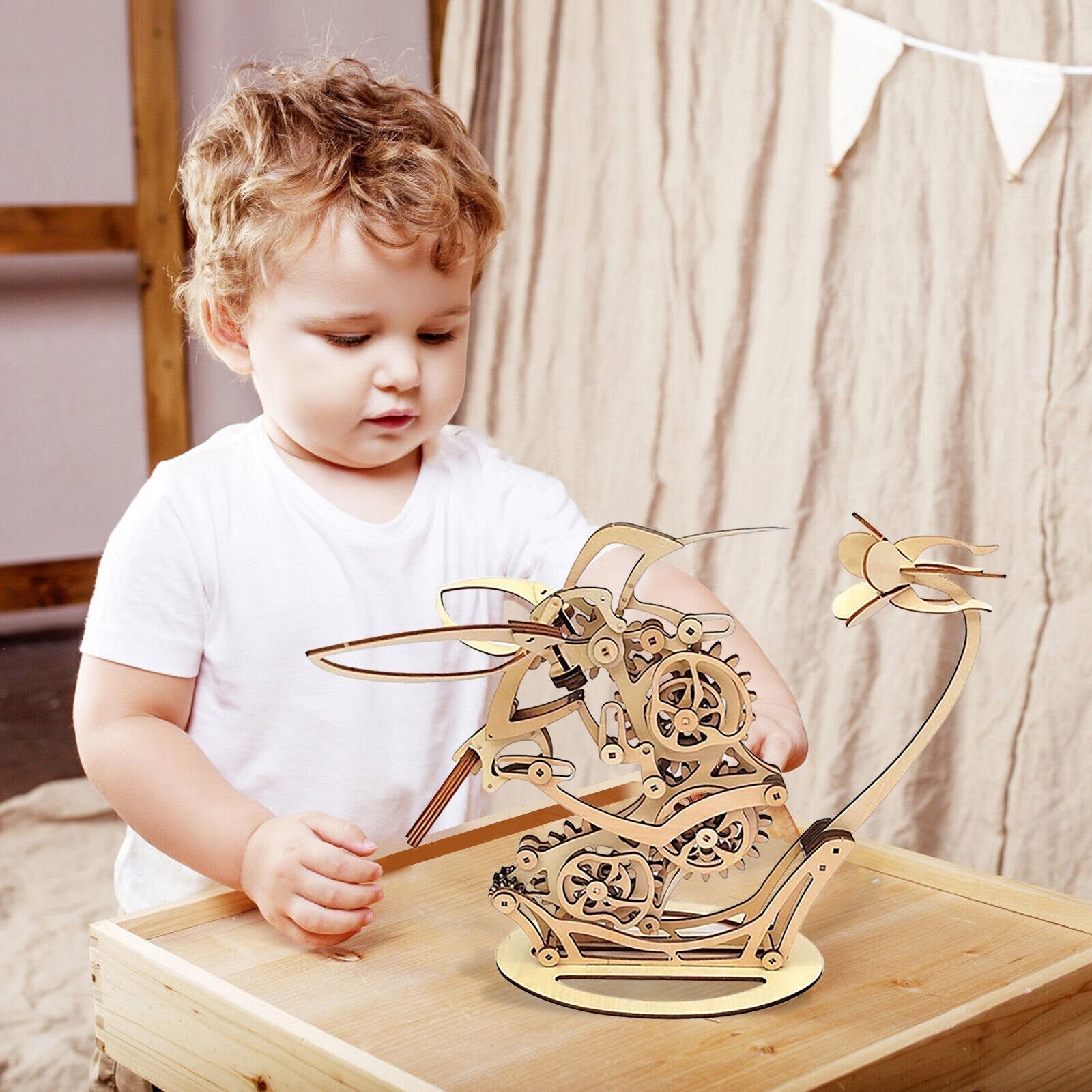 Child playing with a wooden mechanical model on a table