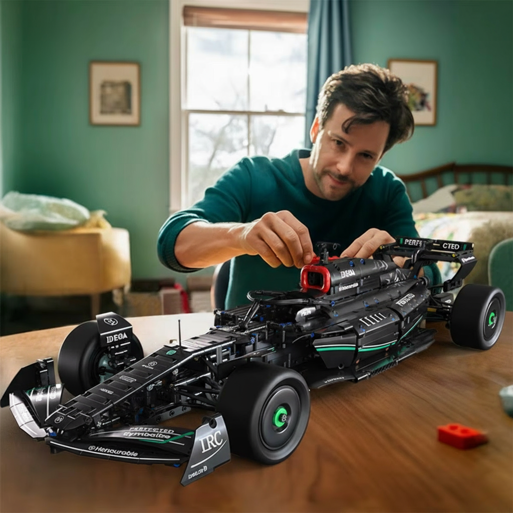 Man assembling a large model of a racing car on a table in a room.