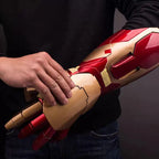 Red and gold mechanical arm prop held by a person against a dark background
