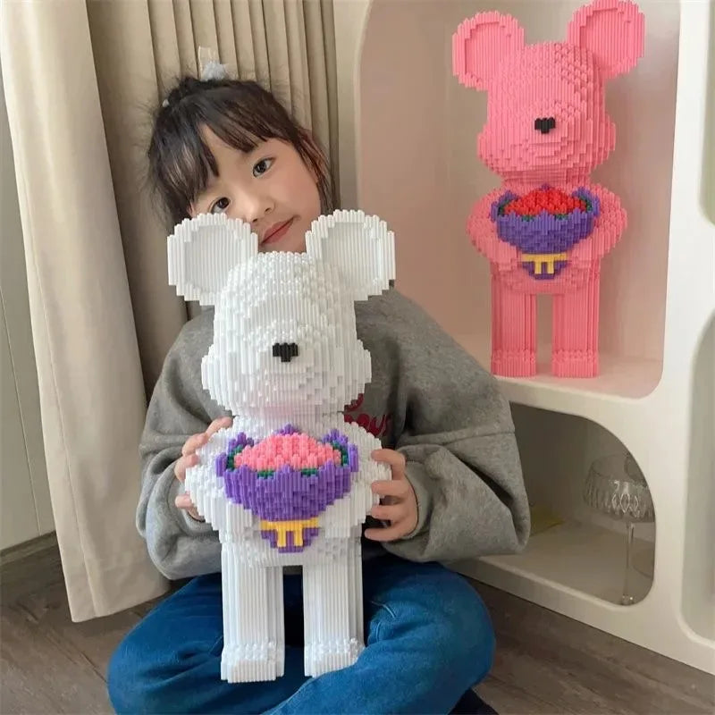 Child holding a white bear-shaped toy with a pink flower, next to a pink bear-shaped toy with a purple flower on a shelf.