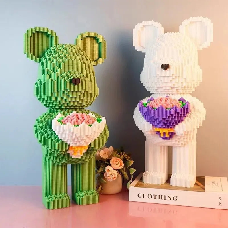 Two bear-shaped decorative items made of interlocking bricks, one green and one white, holding flower bouquets on a pink surface.