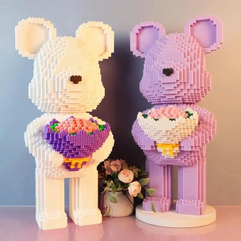 Two bear-shaped decorative items made of interlocking bricks, one white and one pink, holding flower bouquets.