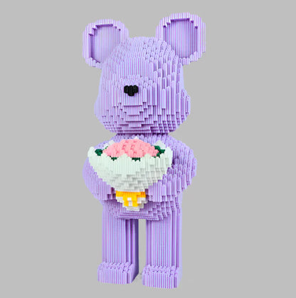 Purple teddy bear made of interlocking bricks holding a bouquet of flowers on a gray background