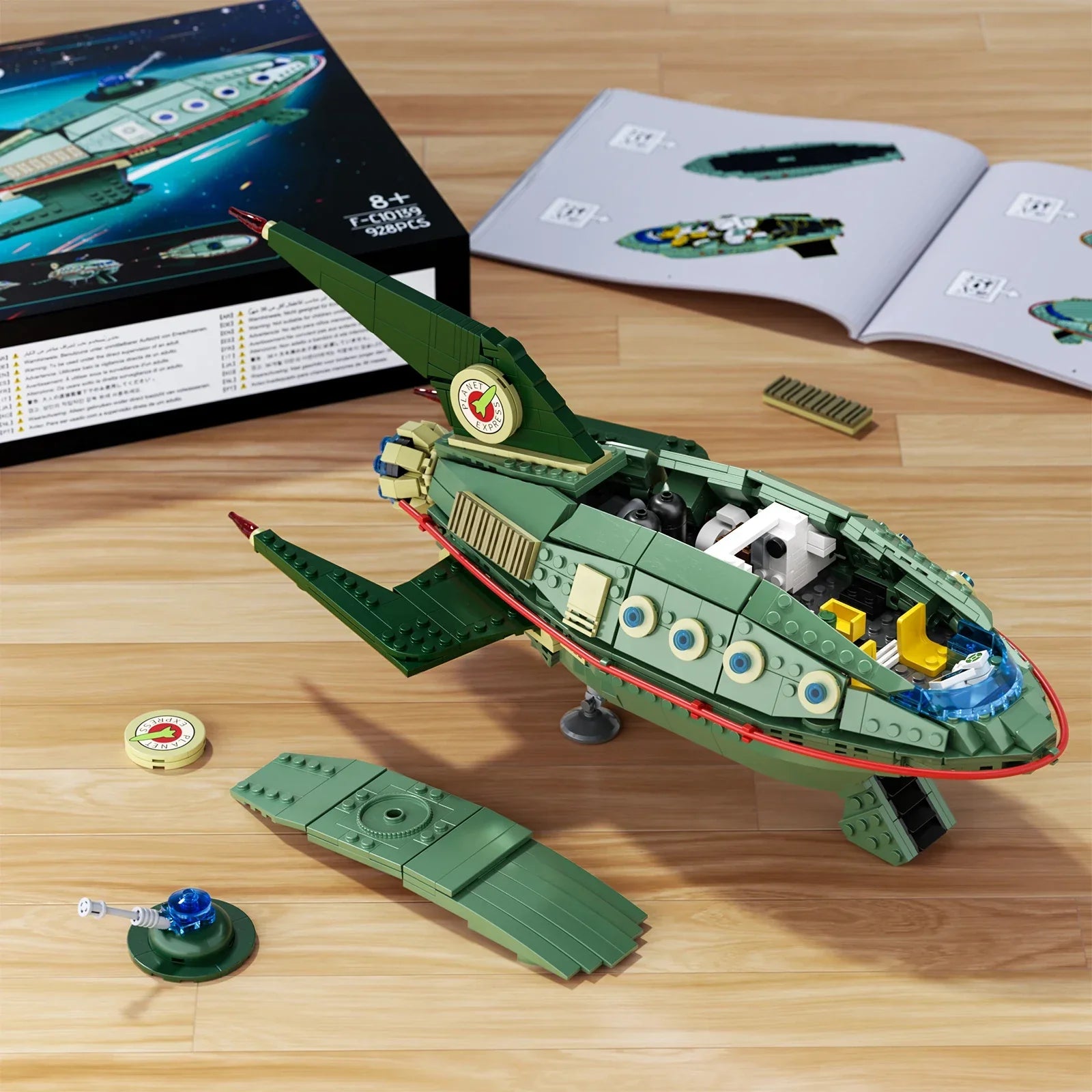 Green toy spaceship model on a wooden surface with packaging and instructions in the background.