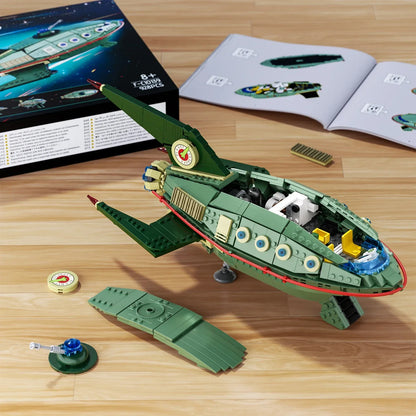 Green toy spaceship model on a wooden surface with packaging and instructions in the background.