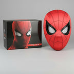 Red superhero spider man mask with black web patterns next to its packaging box on a gray background